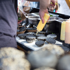 Wall Mural - Chef making  burgers outdoor on open kitchen international food festival event. Street food ready to serve on a food stall.