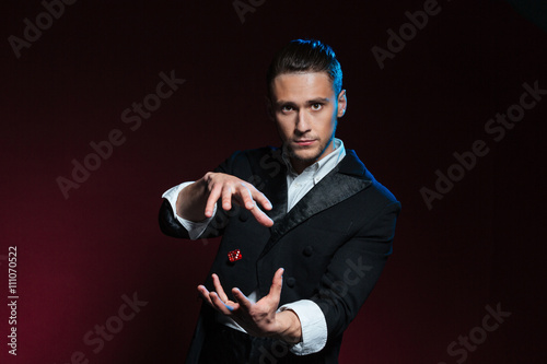 Fotografía Confident young man magician showing tricks using one flying dice