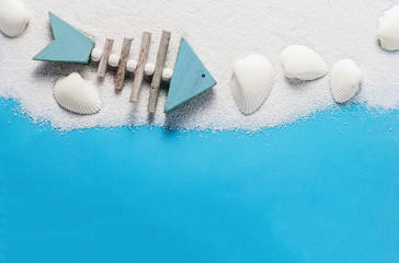 Fish decoration and shells on white sand, background