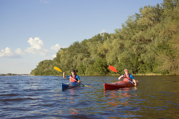 Two guys travel the river on a kayaking in the summer.