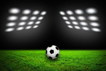 Soccer ball on grass against black background