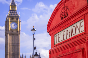 Wall Mural - Classic red British telephone box with the Big Ben at background on a sunny afternoon with blue sky and clouds - London, UK