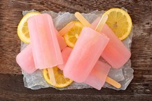 Cluster Of Pink Lemonade Popsicles On Wax Paper With Rustic Wood Background