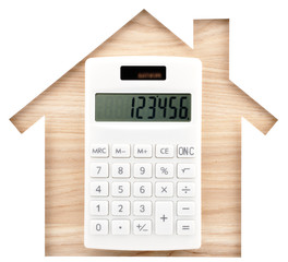 House shaped paper cutout and white calculator on natural wood lumber.
Isolated on white background.
