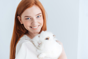 Wall Mural - Cheerful redhead woman posing with rabbit