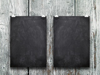 Close-up of two blank blackboard frames hanged by pegs against old light weathered wooden background