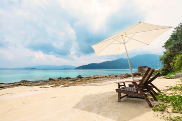 Wall Mural - Beach chairs with parasol on the beach in the island in cloudy day