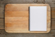 Chopping board and cookbook on wooden background