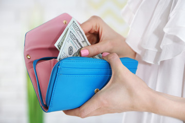 Wall Mural - Young woman getting dollars banknotes from purse