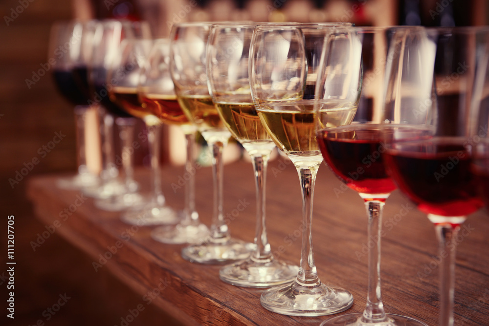 Many glasses of different wine in a row on bar counter