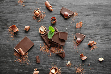 Sticker - Pieces of chocolate with hazelnuts and fresh mint on black wooden background