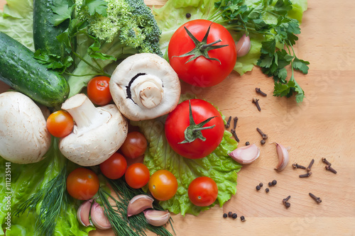 Fotografie, Obraz Vegetables on wood background, mushrooms, cucumbers, tomatoes, broccoli, lettuce