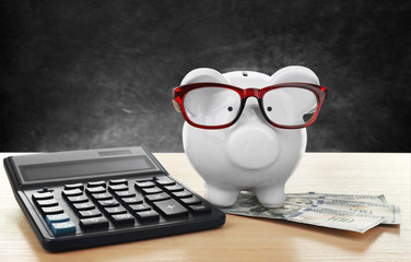 Poster - Piggy bank with dollar banknotes, glasses and calculator on dark background