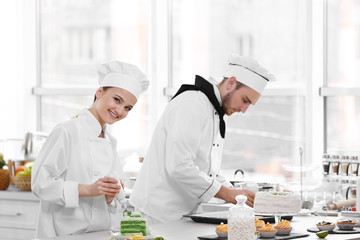 Wall Mural - Male and female chefs working at kitchen