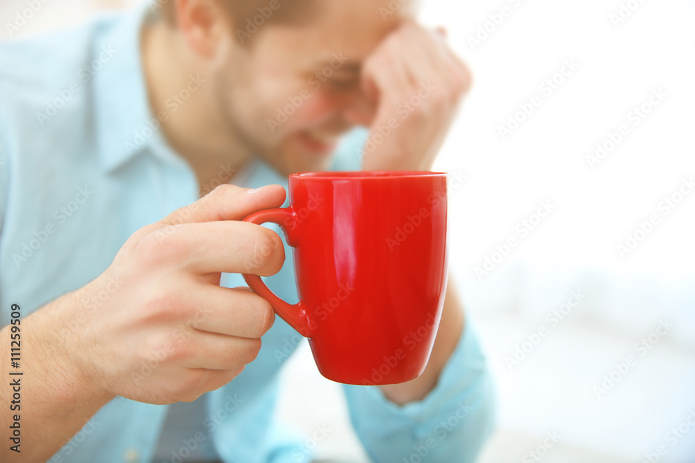 Man holding red cup of coffee in hand, close up