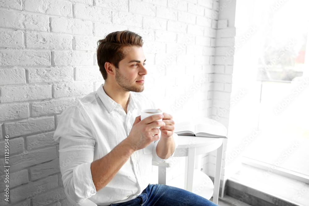 Young man drinking tasty coffee in the morning