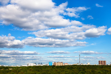 Wall Mural - white cloud in blue sky over city and green forest