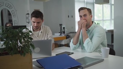 Aufkleber - Young happy man laughs. Men have fun at the working place in the office. Beginner writer working on the computer. 