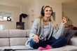 © Nektarstock - Middle aged woman happily listening to music on headphones at home