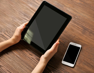 Sticker - Mobile phone and female hands using tablet, on the wooden background