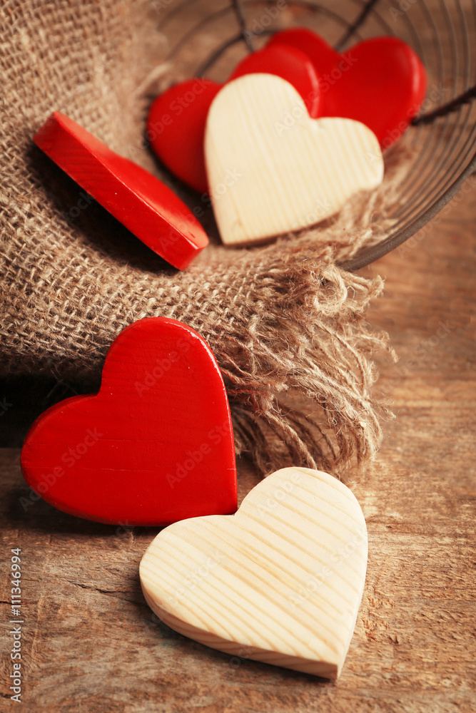 Wooden hearts in wicker basket, on rustic wooden background