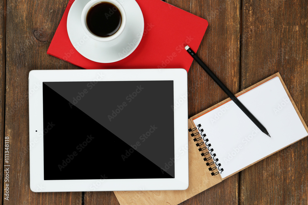 Digital tablet with cup of coffee and notebook on wooden table, closeup