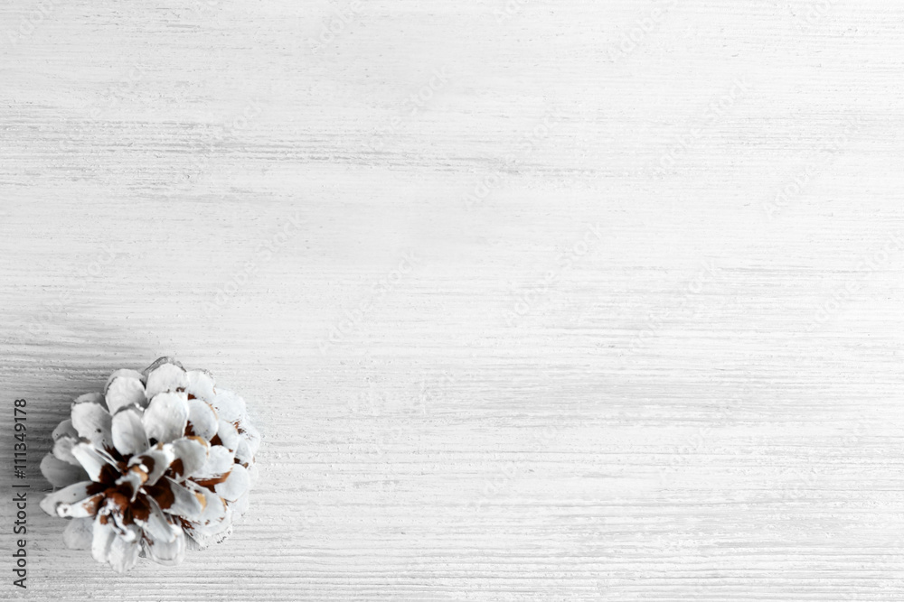 Beautiful simple winter background with pine cone on wooden texture