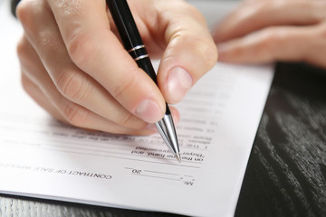 Wall Mural - Male hand with pen signing document at the desk closeup