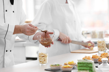 Male chef  pouring chocolate  sauce on a fruit dessert.