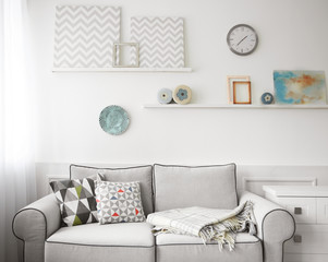 Sticker - Living room interior, grey couch and shelves with paintings on wall background