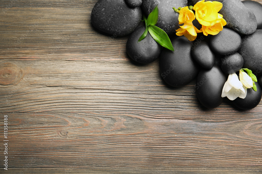 Beautiful spa composition with stones and freesia on wooden background