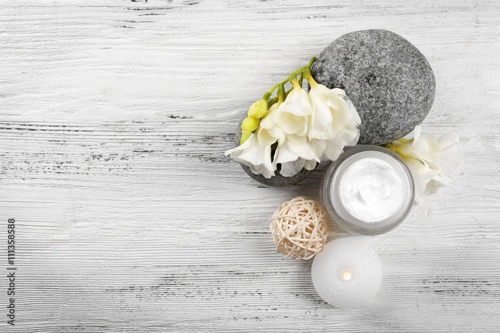 Spa still life with pebbles and cream on wooden table, top view
