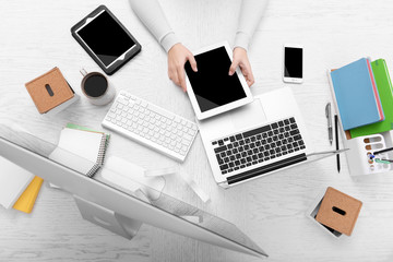 Poster - Concept of using electronics. Businesswoman works at office. Computer, laptop, tablet, cup of coffee and other things on the table. Top view