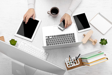 Canvas Print - Concept of using electronics. Businesswoman works at office. Computer, laptop, tablet, cup of coffee and other things on the table. Top view