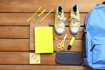 Sticker - School set with backpack, shoes and supplies on wooden background