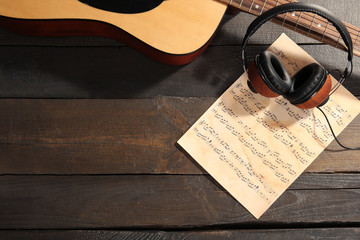 Wall Mural - Guitar and music paper on wooden background