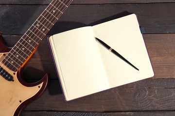 Wall Mural - Guitar and notebook on wooden background