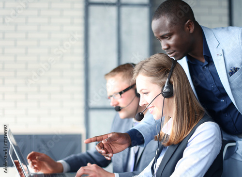 Fotografía Phone operator working at call centre office helping hiss colleague