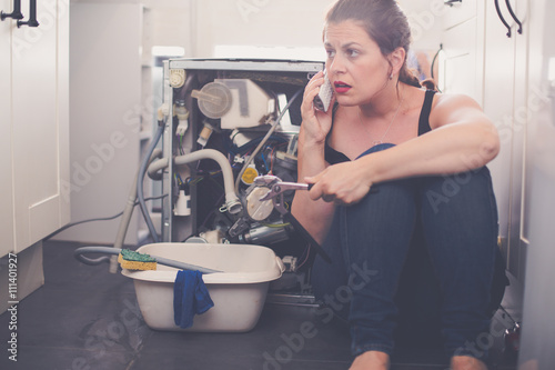 Fotografía La mujer está llamando a un fontanero para reparar la fuga