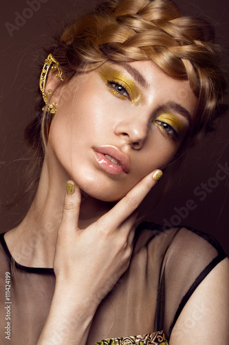 Poster Beautiful girl in a gold dress with creative makeup and braids on her head