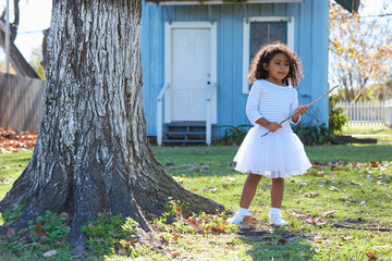 Wall Mural - Kid girl with branch stick playing outdoor