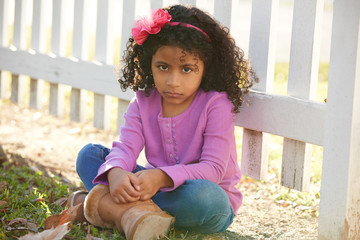 Wall Mural - Sad toddler kid girl portrait in a park fence