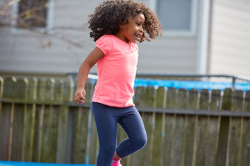 Wall Mural - Kid toddler girl jumping on a playground