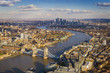 London aerial skyline view including Tower Bridge with red Double Decker Bus, skyscrapers of Canary Wharf and River Thames
