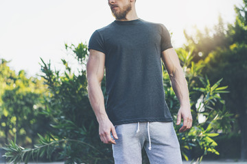 Canvas Print - Photo Bearded Muscular Man Wearing Black Blank t-shirt and shorts in summer vacation. Relaxing time near the lake. Green City Garden Park Sunset Background. Front view. Horizontal Mockup.