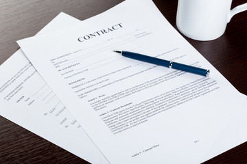 Pen and contract papers on wooden desk