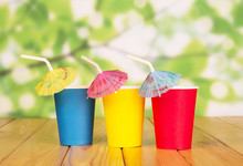 Multi-colored Disposable Paper Cups And Straws On Abstract Green.