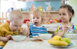 © Andrey Kuzmin - group of children eating from plates in day care centre