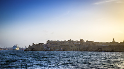 Valletta, Malta - Cruise ship leaving the Grand Harbour of Valletta at sunset