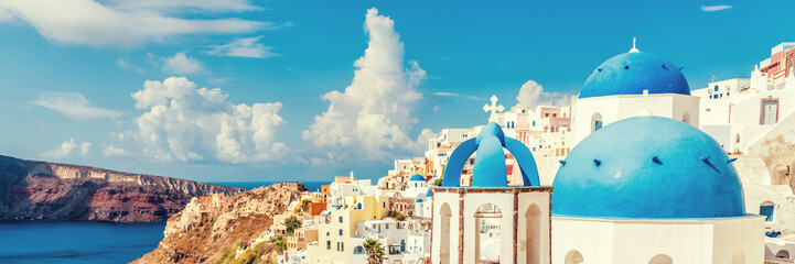 Three Domes church panoramic view of Santorini island, Oia village, Greece. Famous Europe travel european destination greek island. Horizon landscape banner crop for advertisement copyspace.